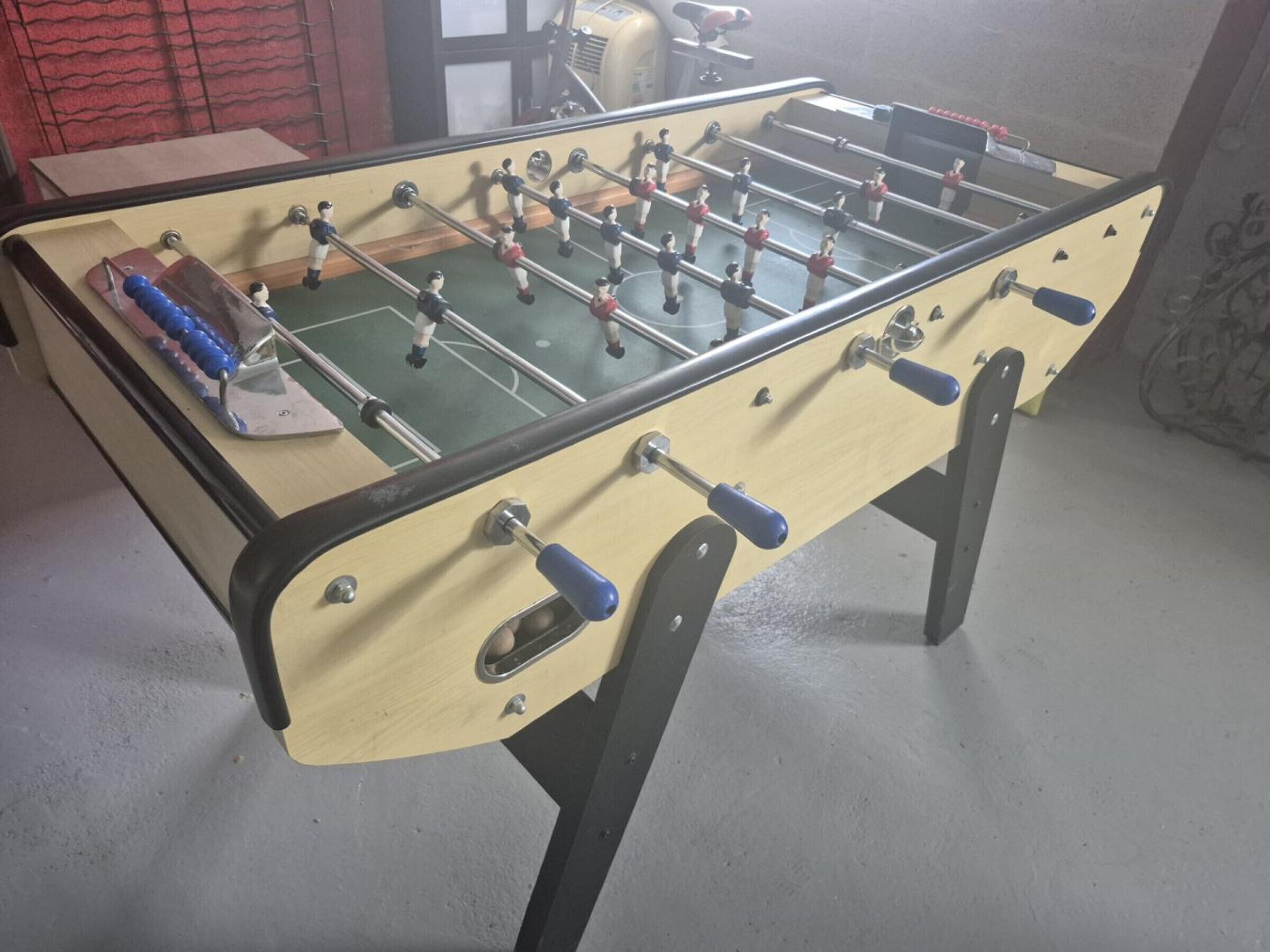 A foosball table with a wooden frame and blue handles.