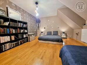 A bedroom with a loft bed, a bookshelf, a dreamcatcher, and a radiator.