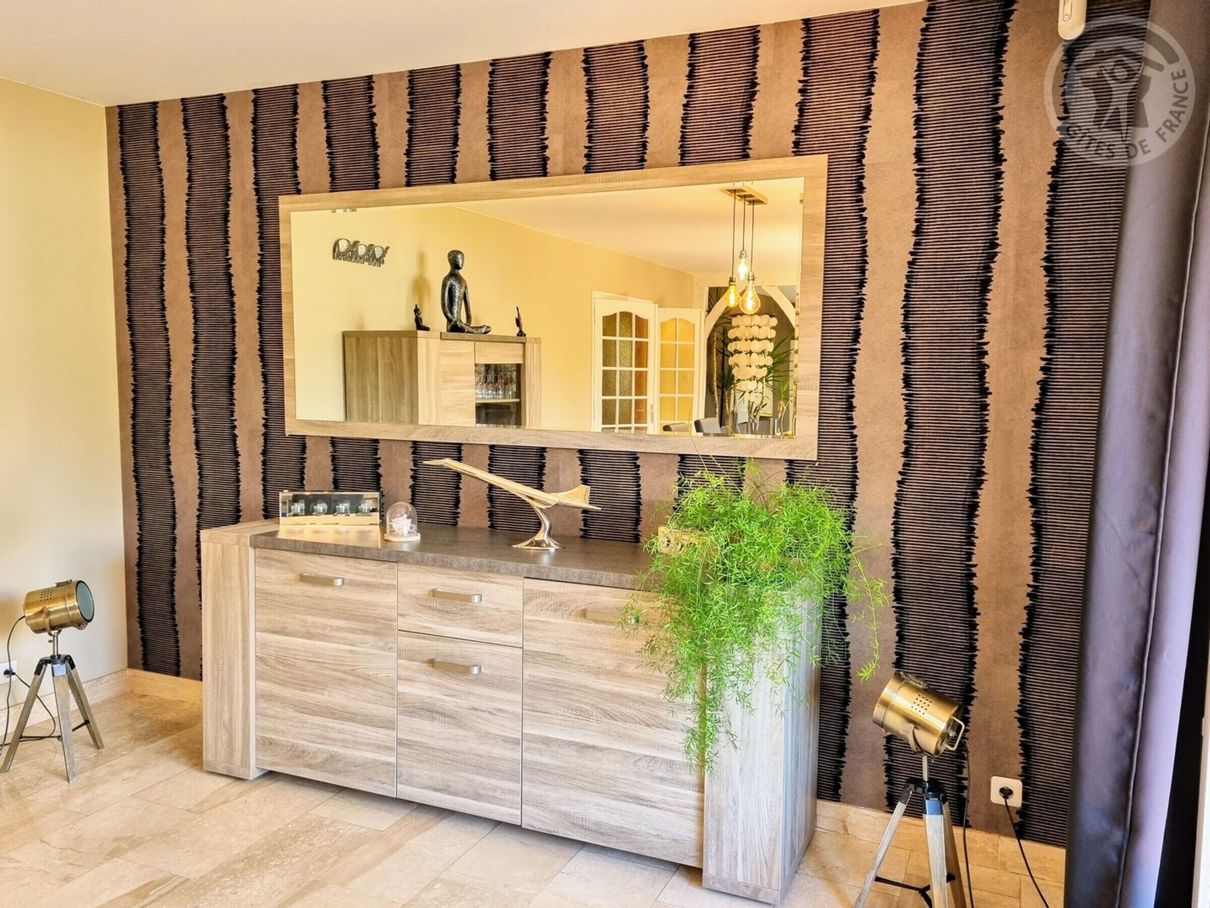 Une salle de bain moderne avec un grand miroir, un meuble-lavabo en bois et une plante en pot.