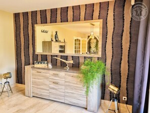 A modern bathroom with a large mirror, wooden vanity, and a potted plant.