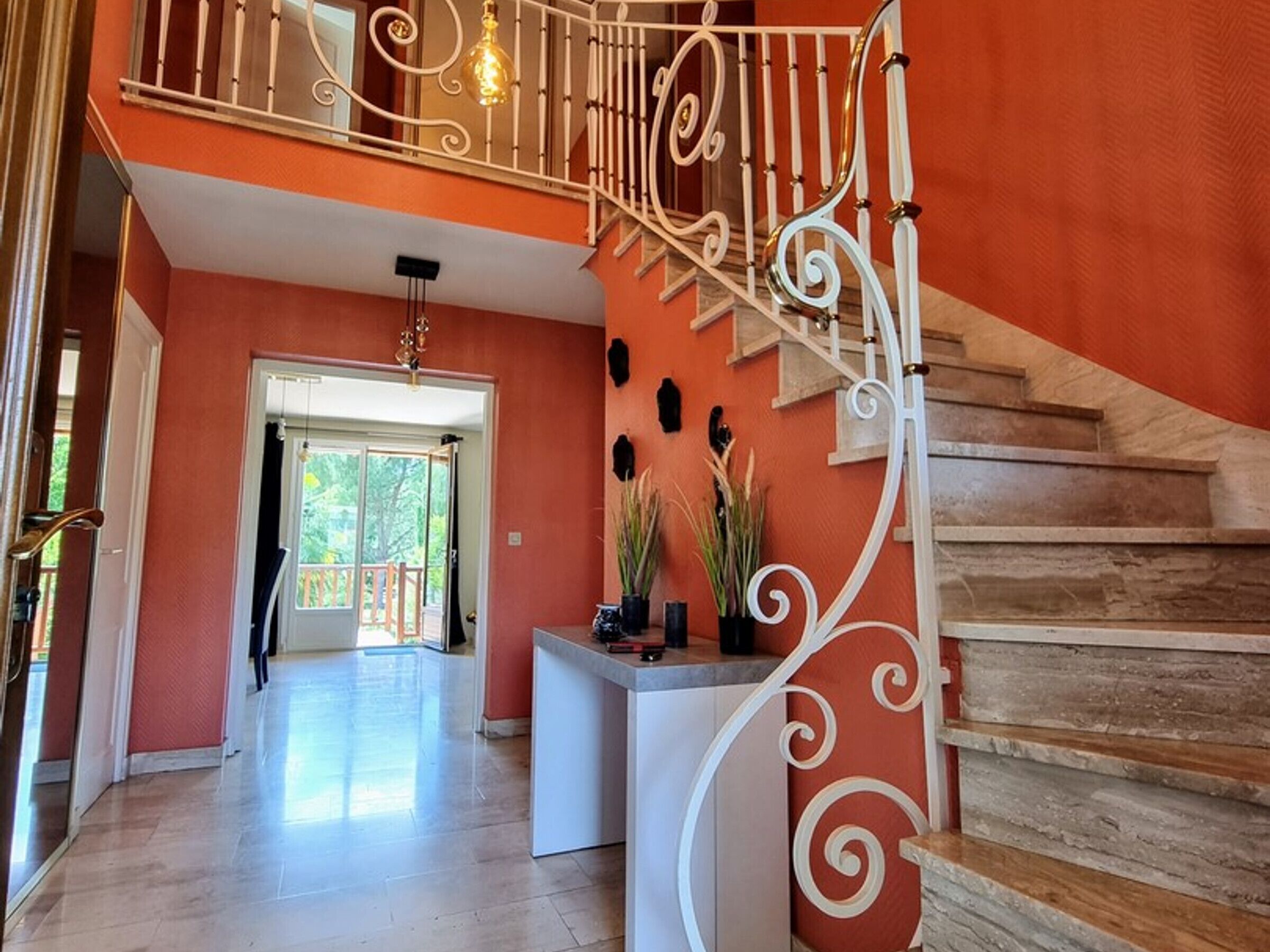 Ein geräumiger Flur mit Treppe, einer Rezeption und Blick ins Freie.