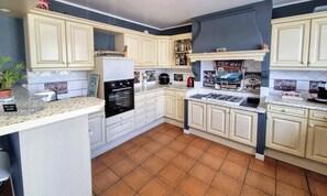 A kitchen with white cabinets, a stove, an oven, and a tiled backsplash.