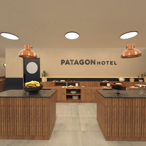 A hotel reception area with a wooden reception desk, a wall-mounted sign reading 'PATAGON HOTEL,' and a fruit bowl on the counter. - Patagon Hotel (El Calafate)