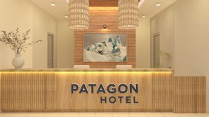 Una recepción con detalles de madera, un cuadro grande enmarco con icebergs, y el texto 'PATAGON HOTEL' en la pared.