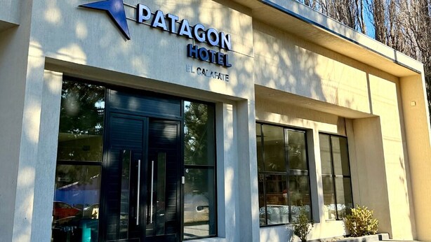 Un hotel llamado 'Patagon Hotel' con una fachada moderna, ventanas grandes y un logotipo sobre la entrada.