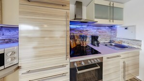 A modern kitchen with a built-in oven, a coffee maker, and a stone backsplash. - Exclusive Apartment for 4 People (56 m²) in Schalkenmehren with Lake View (Schalkenmehren)