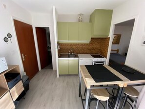 Eine kleine Küche mit grünen Schränken, einem Herd und einem Spülbecken.