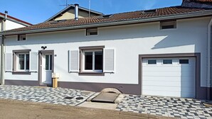 A two-story house with a garage, a tiled entrance, and a small window with shutters. - Spacious house - 6 guests (Tignécourt)