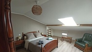 A bedroom with a wooden bed, a green leather chair, a small table, a ladder, and a skylight. - Spacious house - 6 guests (Tignécourt)