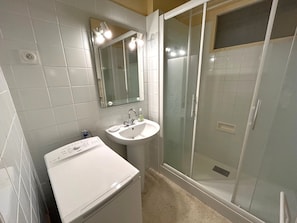 A bathroom with a white sink, mirror, and glass shower enclosure. - Apartment 4 guests with sea view (Argelès-sur-Mer)