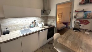 Une cuisine compacte équipée d’un évier, d’un grille-pain et d’une machine à café. On y trouve une chaise et une petite table.
