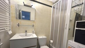 Une salle de bain équipée d’un lavabo, de toilettes et d’un lave-linge.