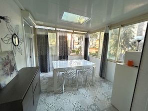 Ein Zimmer mit Dachfenster, einem Esstisch mit Stühlen, einem gemusterten Boden und Blick ins Freie.