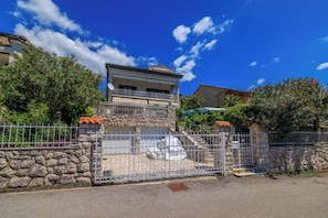 Ein zweistöckiges Haus mit Natursteinfassade, einem Balkon und einem begrenzten Auffahrtsweg.