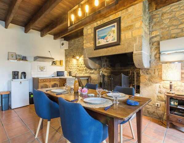 Ein Essbereich mit Steinwand, Kamin und einer Küche im Hintergrund.