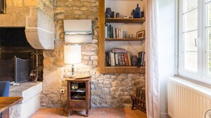 Una camera accogliente con una parete in pietra, un camino, una libreria e una finestra.