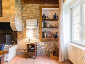 Ein gemütliches Zimmer mit Steinwand, Kamin, Bücherregal und Fenster.