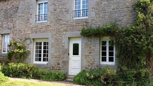 Un edificio in pietra con diverse finestre e una porta bianca.