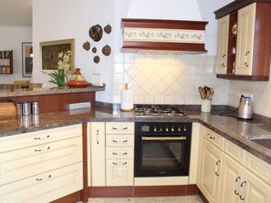 A kitchen with a gas stove, oven, and a countertop with a sink. - Cozy Moraira Apartment with Shared Pool, Garden, and Close to Beach (Moraira)