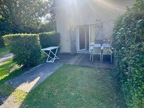 A patio with a table and chairs, a sliding glass door, and a hedge. - Country house - 2 guests (Auberville)