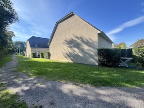 A residential building with a sloped roof, a gravel driveway, and a well-maintained lawn. - Country house - 2 guests (Auberville)