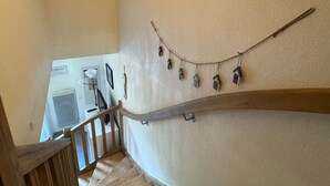 Una escalera con barandilla de madera, un aire acondicionado de pared y una guirnalda de casas para pájaros colgantes.
