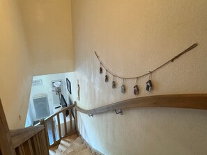 A staircase with a wooden handrail, a wall-mounted air conditioning unit, and a string of hanging birdhouses. - Country house - 2 guests (Auberville)