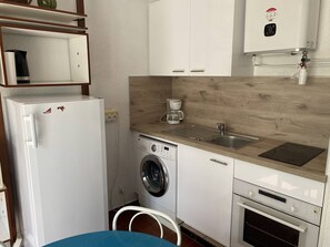 A compact kitchen with a refrigerator, washing machine, coffee maker, sink, and oven. - Ground floor apartment with parking - 4 guests (Le Barcarès)