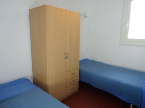 A room with a wooden wardrobe, two single beds, and a window. - Ground floor apartment with parking - 4 guests (Le Barcarès)