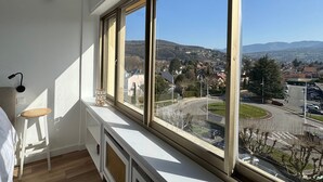A room with a large window, a radiator, a small stool, and a lamp.