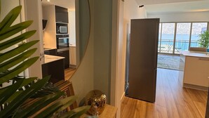 A modern kitchen with built-in appliances, a dining area, and a view of the sea.