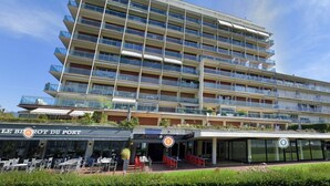 A multi-story hotel with balconies, outdoor seating, and a restaurant named 'LE BIRROT DU PORT' at the ground level.
