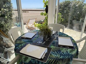 Ein Tisch für zwei Personen mit Blick auf den Strand, eine Topfpflanze und ein Glas Wasser.
