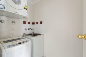 A laundry area with a washing machine, a sink, and a ventilation unit. - Bright 2-bed Retreat Near Darling Harbour (Sydney)