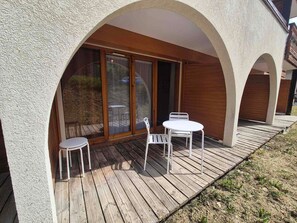 A covered outdoor area with a wooden deck, two white tables, and chairs. - Studio, pets allowed - 2 guests (Valloire)