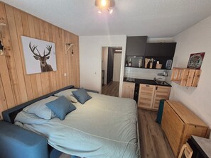 A bedroom with a bed, a desk, and a kitchenette. - Studio, pets allowed - 2 guests (Valloire)