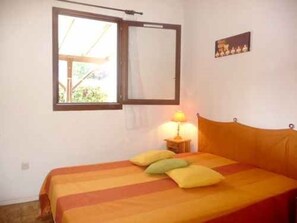 Ein Zimmer mit einem Bett, einem Fenster, einem Wandbild und einer Nachttischlampe.