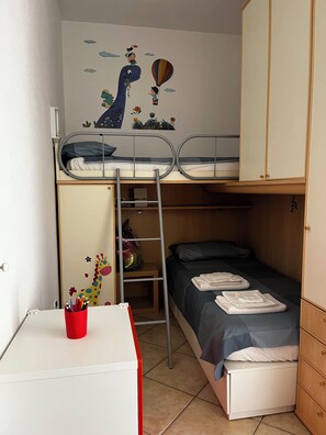 Une chambre avec un lit superposé, un bureau, une armoire et un motif décoratif sur le mur.