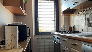 A compact kitchen with a window, built-in cabinets, a stove, and a dishwasher.