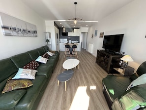 Una sala de estar moderna con un sofá verde, una mesa de centro blanca y un televisor.