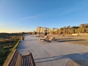 Un espacio al aire libre con pavimento, bancos, una mesa de picnic y un edificio al fondo.