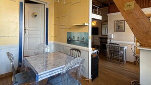 A dining area with a marble table, chairs, a chandelier, and a staircase with wooden beams. - Quirky apartment, pets - 2 guests, mountain and lake view (Aix-les-Bains)