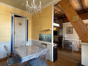 Ein Essbereich mit einem Marmortisch, Stühlen, einer Chandelier und einer Treppe mit Holzbalken.