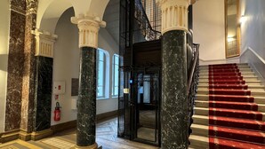A grand staircase with red carpet, marble columns, and a black metal railing. - Quirky apartment, pets - 2 guests, mountain and lake view (Aix-les-Bains)