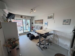 Ein gemütlicher Wohnbereich mit einer Küchenzeile, einer Essecke mit Tisch und Stühlen, einer Couch und einem großen Fenster mit Blick nach draußen.