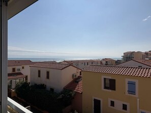Ein Küstenwohngebiet mit terrakotta-gedeckten Häusern, blauem Himmel und Blick auf das Meer.