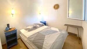 Et soveværelse med seng, to sengeborde, en hat på væggen og et vindue.