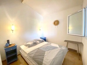 A bedroom with a bed, bedside tables, a wall-mounted hat, and a window. - Holiday villa near the beach - 6 guests (Le Barcarès)