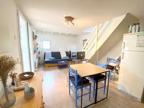 A compact living space with a sofa, a dining table, a computer, and a refrigerator. - Holiday villa near the beach - 6 guests (Le Barcarès)