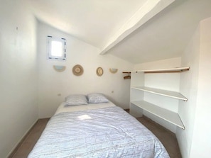 Une chambre à coucher avec un lit, une fenêtre et une étagère fixée au mur.